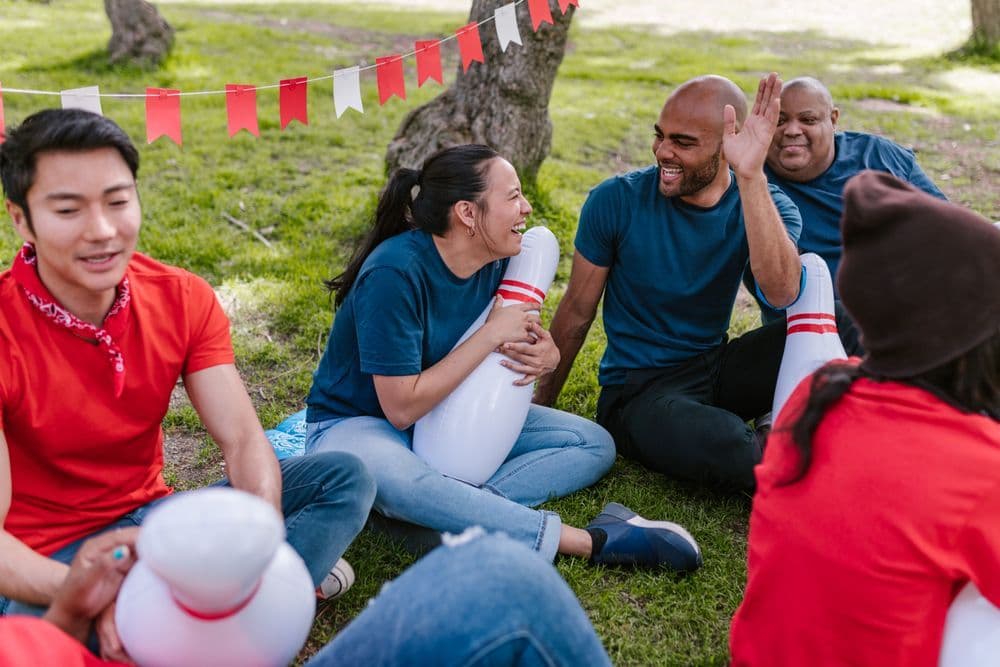A group of adults laughing together during an outdoor lawn game