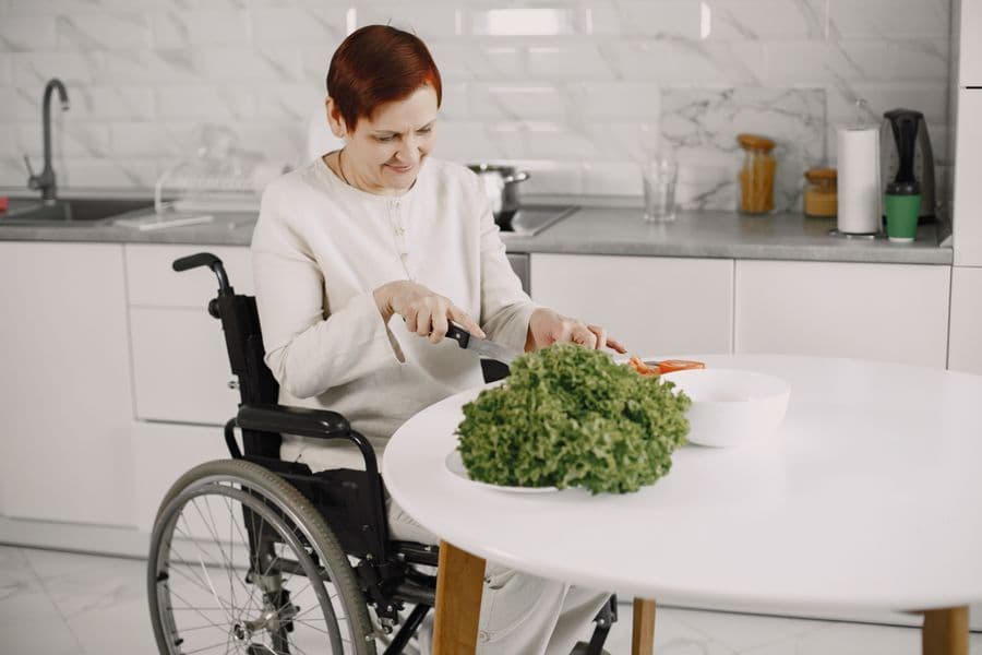 A woman who uses a wheelchair preparing fresh greens at her kitchen table
