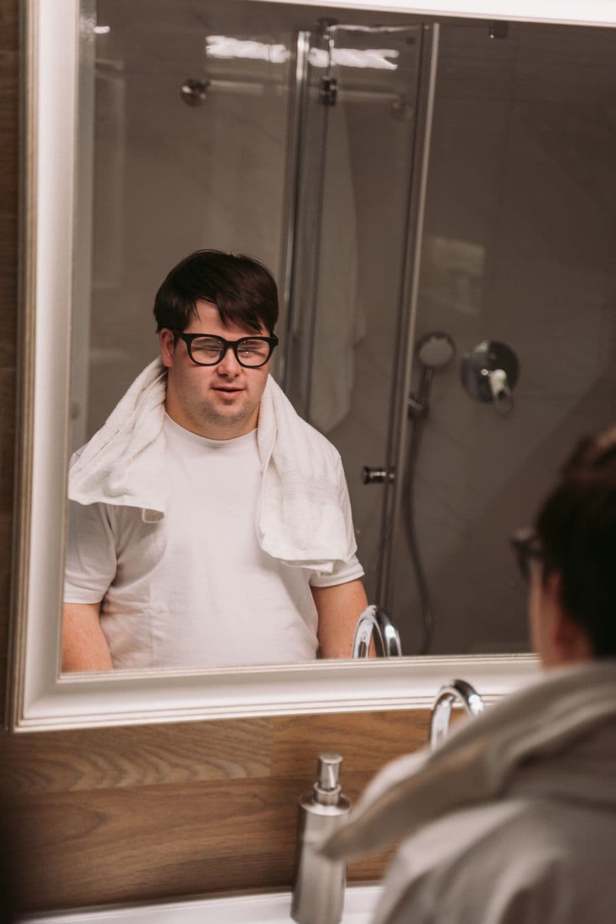 A young man with Down syndrome starting his morning routine at the bathroom mirror